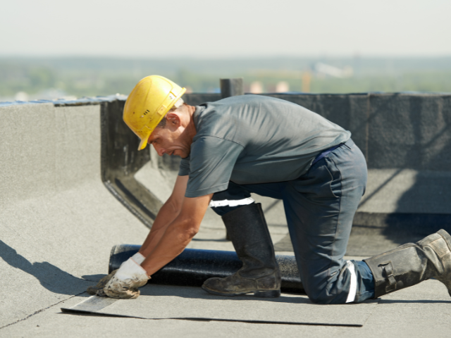 A roofer performing some preventative roof maintenance on a commercial roof.